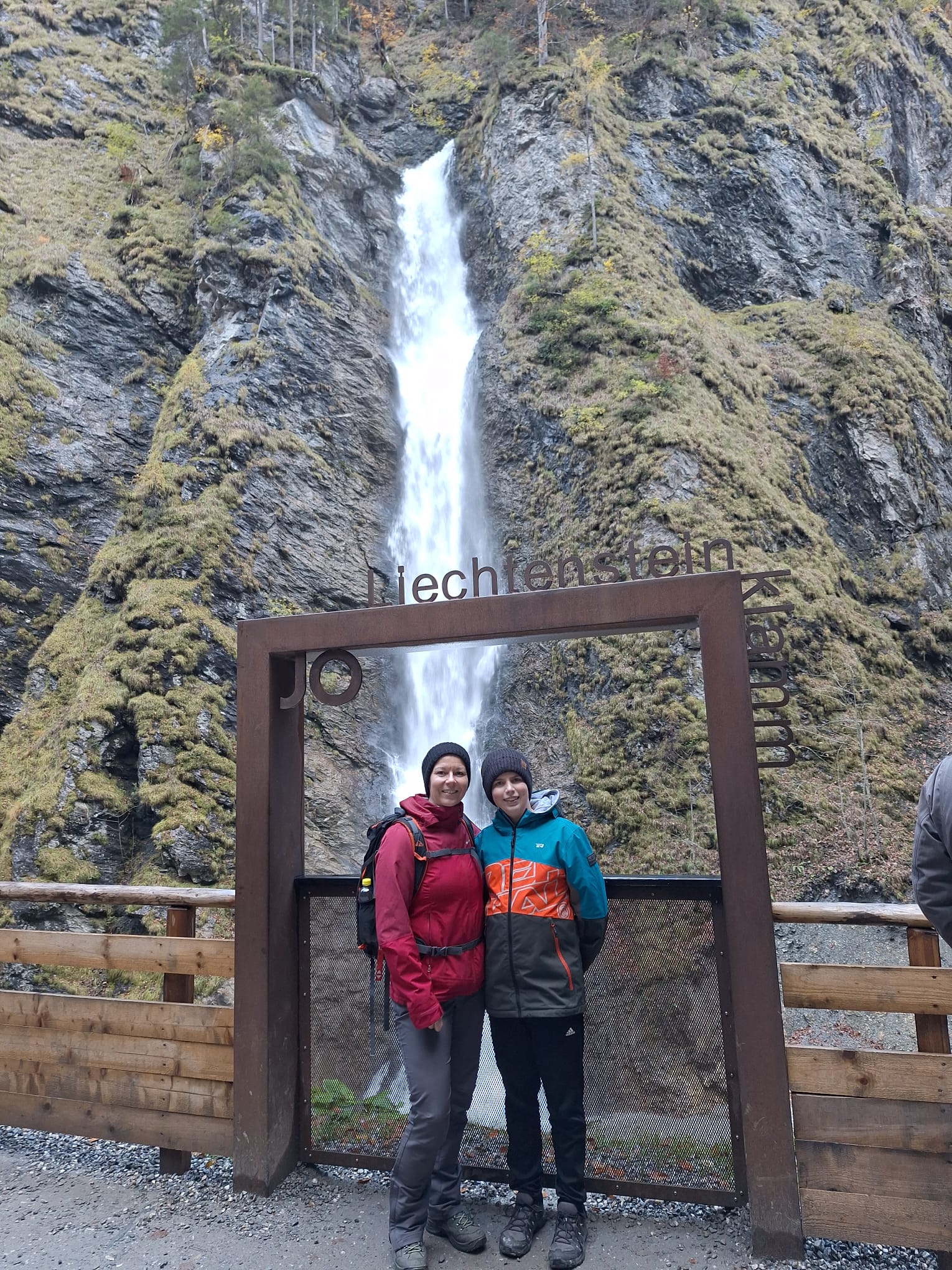 Ein Bild von einem Jungen und seiner Mutter vor einem Wasserfall